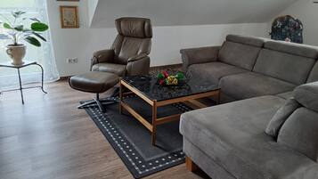 En moderne stue med en læderlænestol, en sofa, et sofabord og en potteplante.