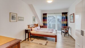 Une chambre à coucher comprenant un lit, des tables de chevet, une chaise et une fenêtre avec des rideaux.