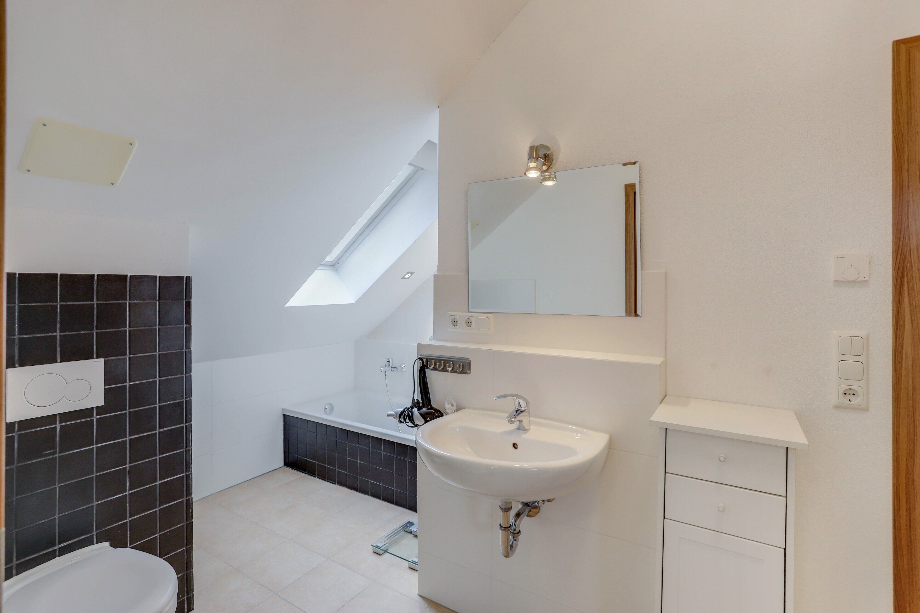 A modern bathroom with a white sink, a mirror, and a bathtub.