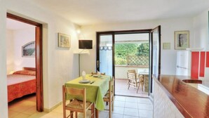 Una habitación con mesa de comedor, sillas, cama, televisor y balcón con vistas.