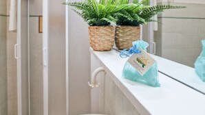 A bathroom with a white sink, two potted ferns, and a gift bag on the counter. - Well-kept and with great views - Appartamenti Le Querce - Melograno (Capoliveri)