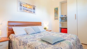 A bedroom with a bed, nightstand, bedside table, and a wardrobe. - Well-kept and with great views - Appartamenti Le Querce - Melograno (Capoliveri)