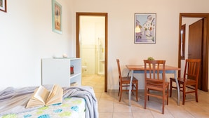 A bedroom with a bed, a bedside table, a bookshelf, and a desk with two chairs. - Well-kept and with great views - Appartamenti Le Querce - Melograno (Capoliveri)