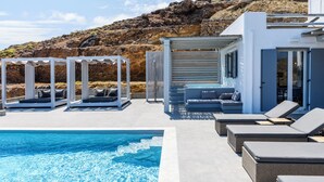 Zona de piscina con sillones de descanso y un jacuzzi, con vistas a una ladera rocosa.