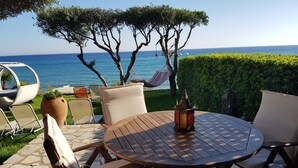 Una mesa redonda de madera con sillas, un farol y vista al mar.