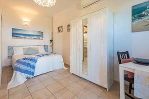 Une chambre à coucher comprenant un lit, une armoire, un bureau et un luminaire fixé au mur.