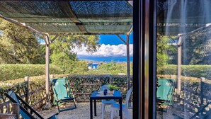 Un área de estar al aire libre con mesa y sillas, una pérgola y vistas al paisaje.