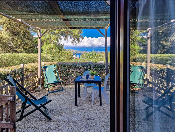 An outdoor seating area with a table and chairs, a pergola, and a view of the landscape.