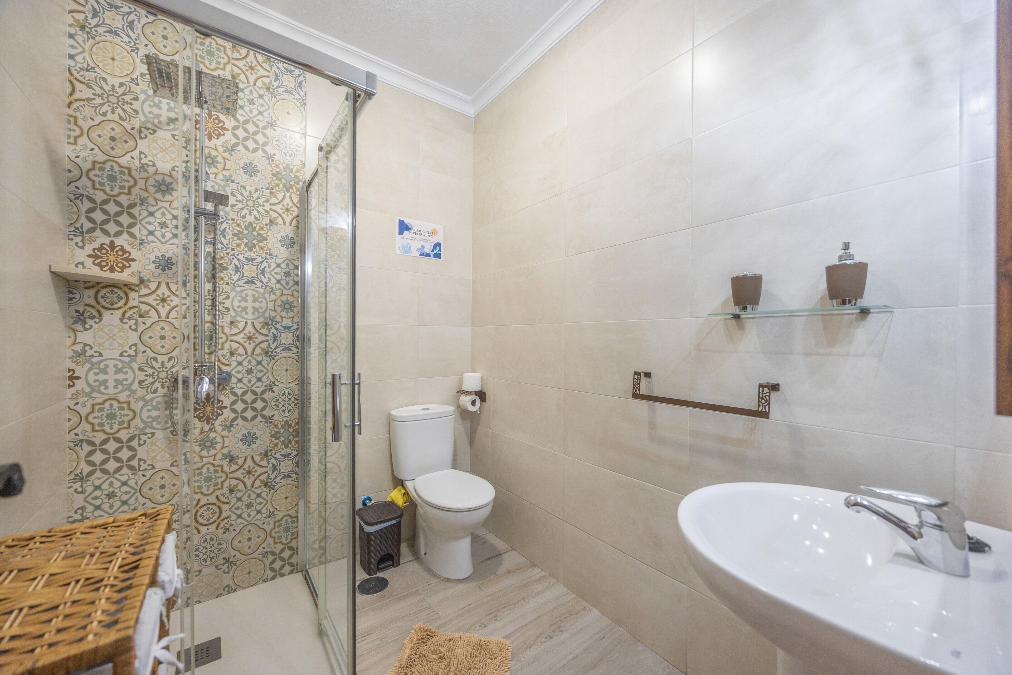 Un bagno con doccia, wc, lavandino e piastrelle decorative.
