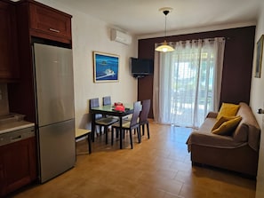 Ett kompakt bostadsutrymme med ett litet kök, en matplats och en soffa.
