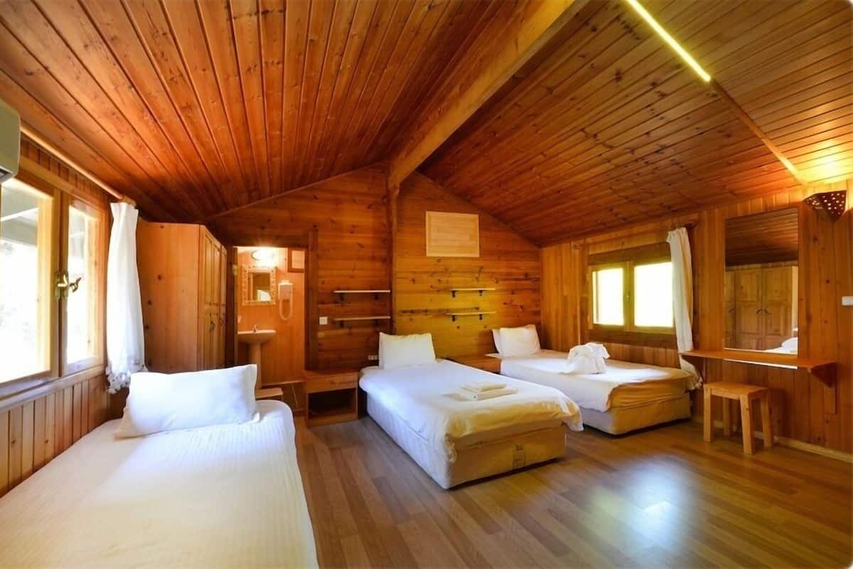 A wooden cabin with three beds, a sink, and a mirror.
