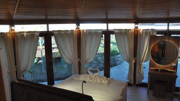 Un dormitorio con cama, cortinas, un espejo y vistas al exterior.