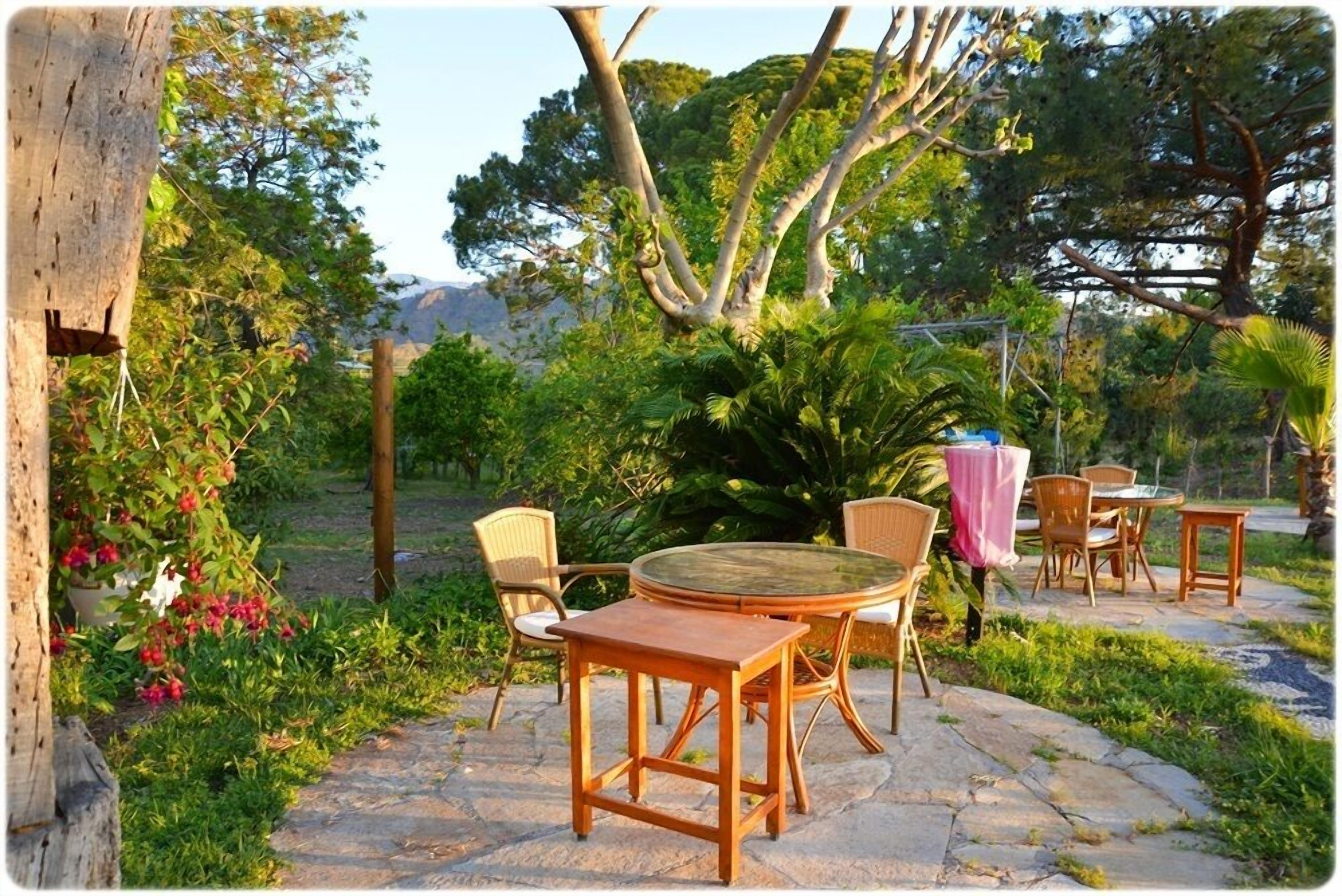 An outdoor patio with stone flooring, wicker furniture, and a view of a mountainous landscape.