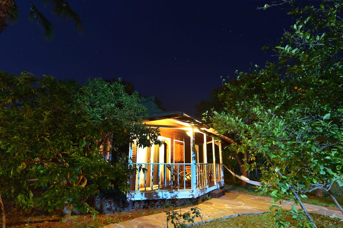 A house with a porch, surrounded by trees and a stone pathway.