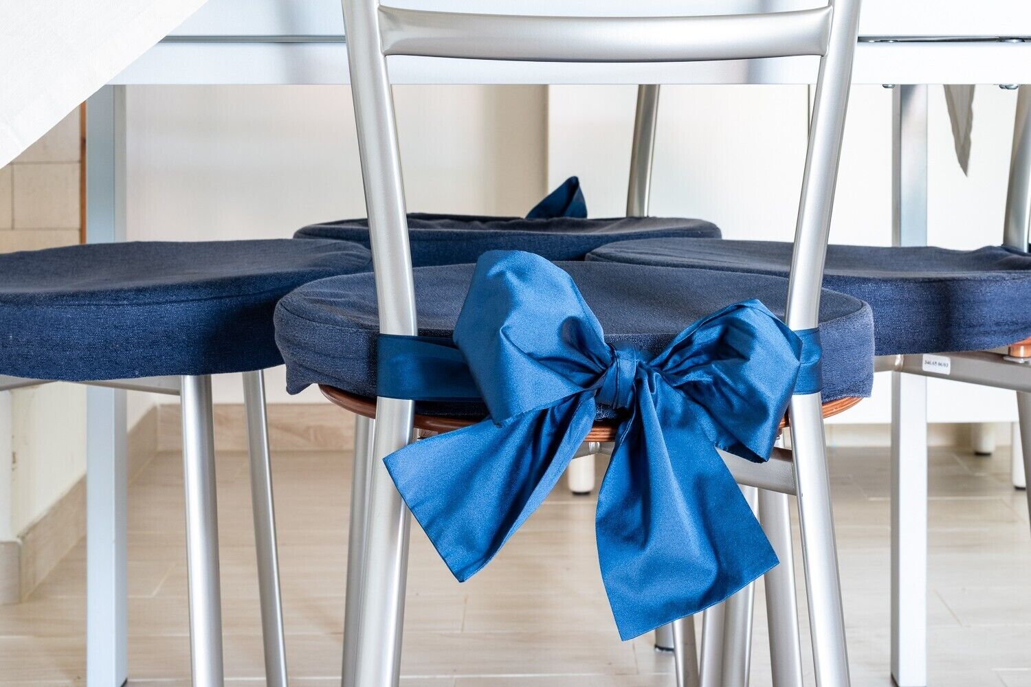 A chair with a blue cushion and a large blue bow.