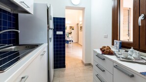 Une cuisine équipée d’une cuisinière, d’un évier et de placards, qui donne sur un coin repas avec des chaises et une table.