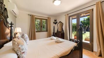 Habitación de hotel con cama, mesita de noche, lámpara, espejo y vista al exterior.