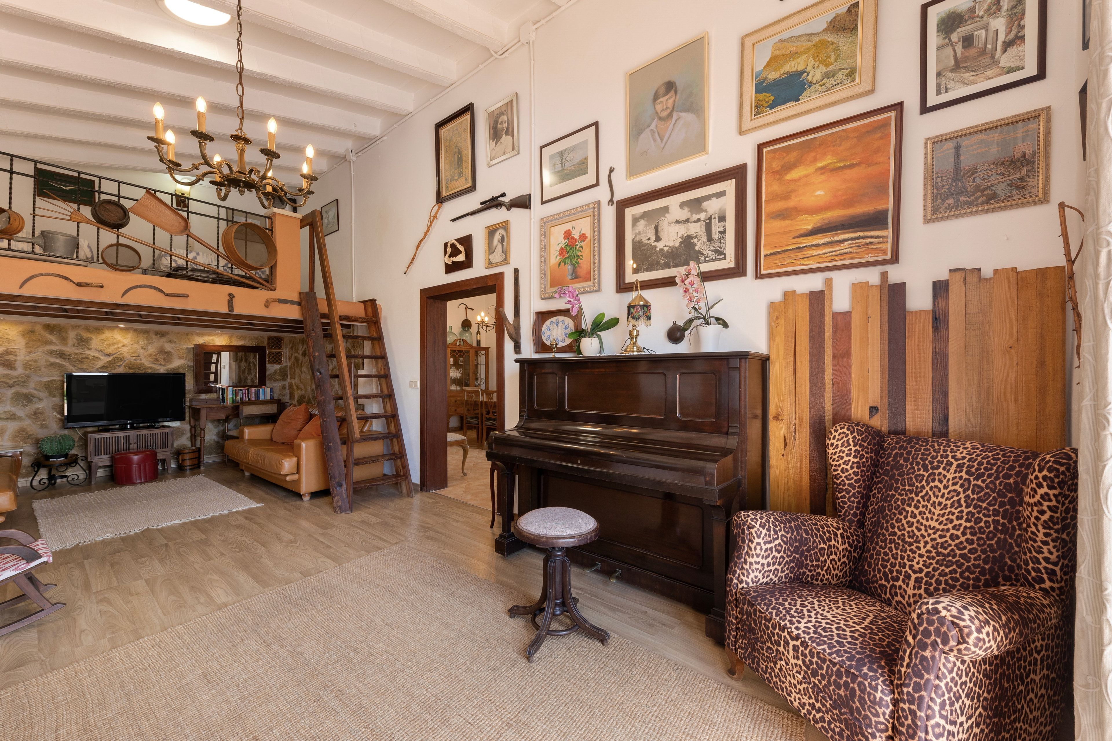 Un salon chaleureux avec un piano, un canapé à motifs léopard et divers tableaux encadrés accrochés au mur.