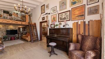 Un salon chaleureux avec un piano, un canapé à motifs léopard et divers tableaux encadrés accrochés au mur.