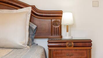 A neatly made bed with a pillow and a bedside table with a lamp.
