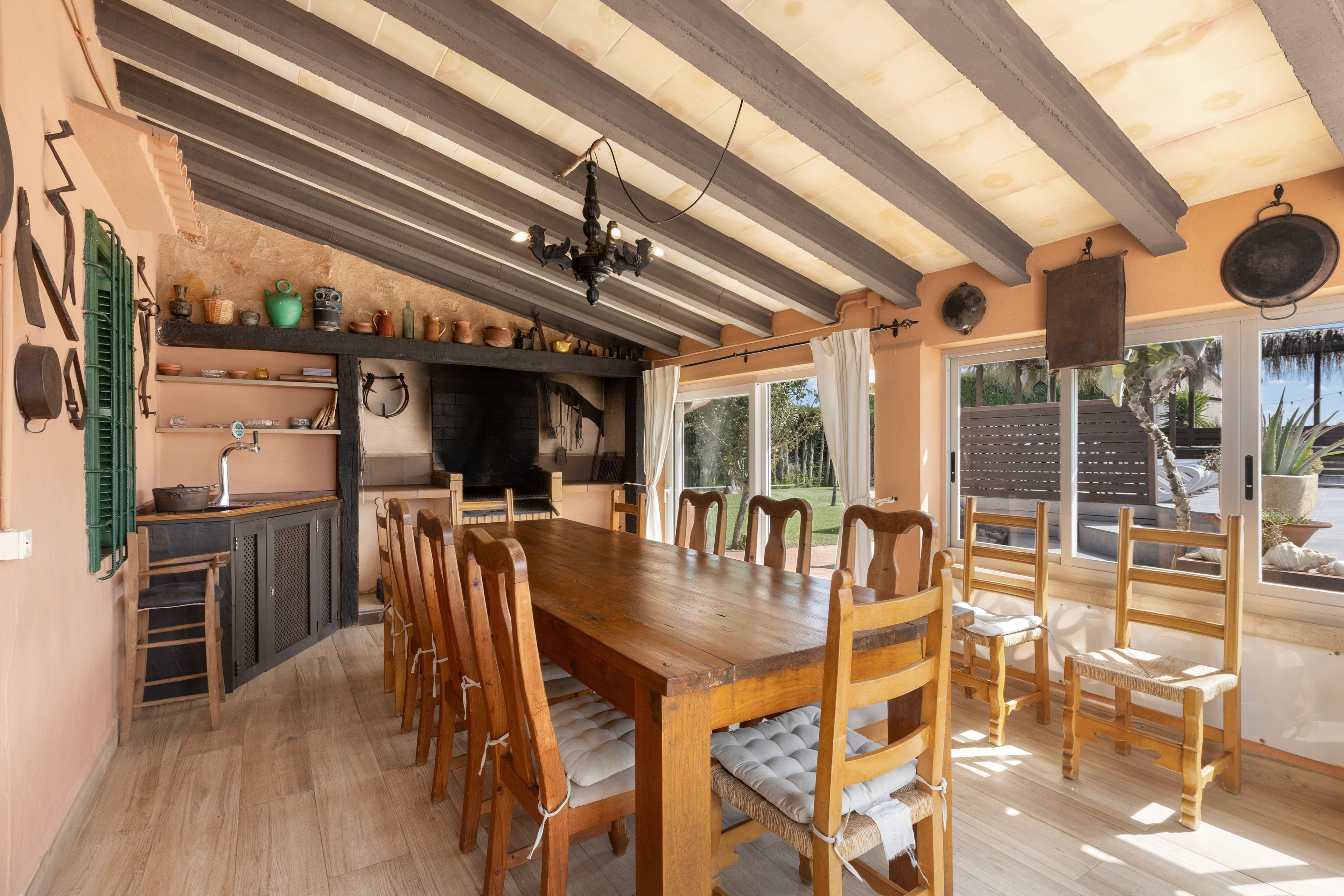 Una cocina rústica con vigas de madera, una gran mesa de madera y diversos utensilios de cocina.