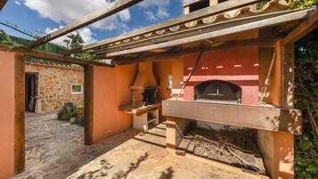 Un bâtiment en pierre doté d’un four en briques, d’une pergola en bois et d’un chemin en pierre.