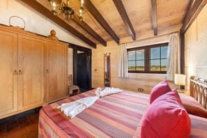 A room with a bed, wooden wardrobe, and a window with a view.