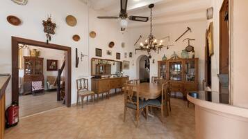 A spacious dining area with a wooden table and chairs, a chandelier, and various decorative items on the walls.