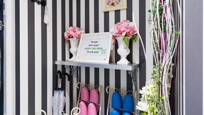 Un couloir aux murs rayés, un porte-chaussures et un panneau indiquant qu’il faut enlever ses chaussures.