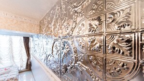 Une pièce aux boiseries murales richement décorées et métalliques, et un lit agrémenté d’une literie à motifs floraux.