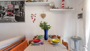 Ruokailutila, jossa on kahdelle katettu pöytä, sininen maljakko, jossa on kukkia, ja mustavalkoinen valokuva seinällä.