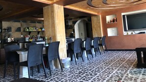 A restaurant with a modern interior, featuring a bar area, seating with chairs and tables, and a patterned floor.