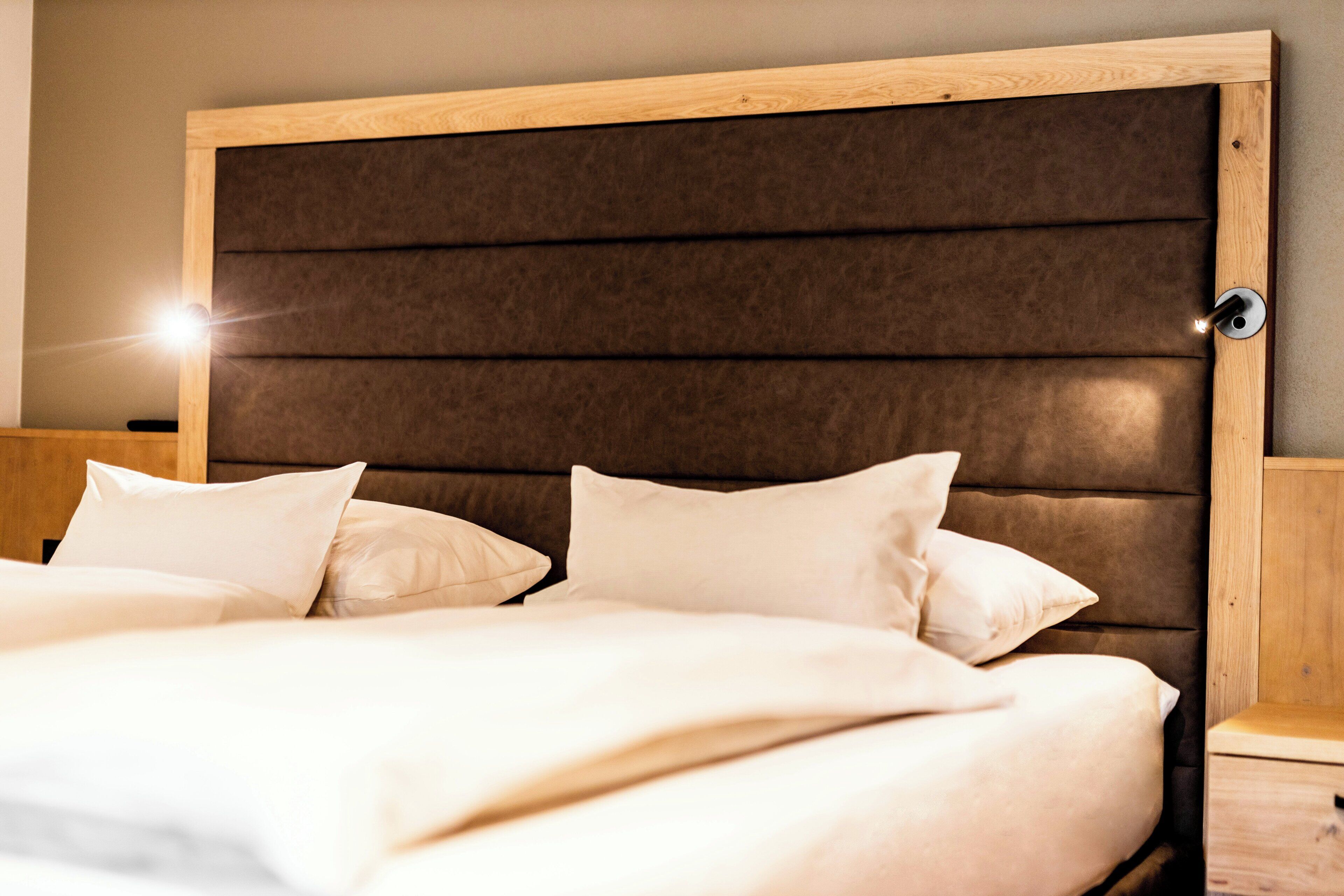 A bed with a wooden headboard and two pillows.