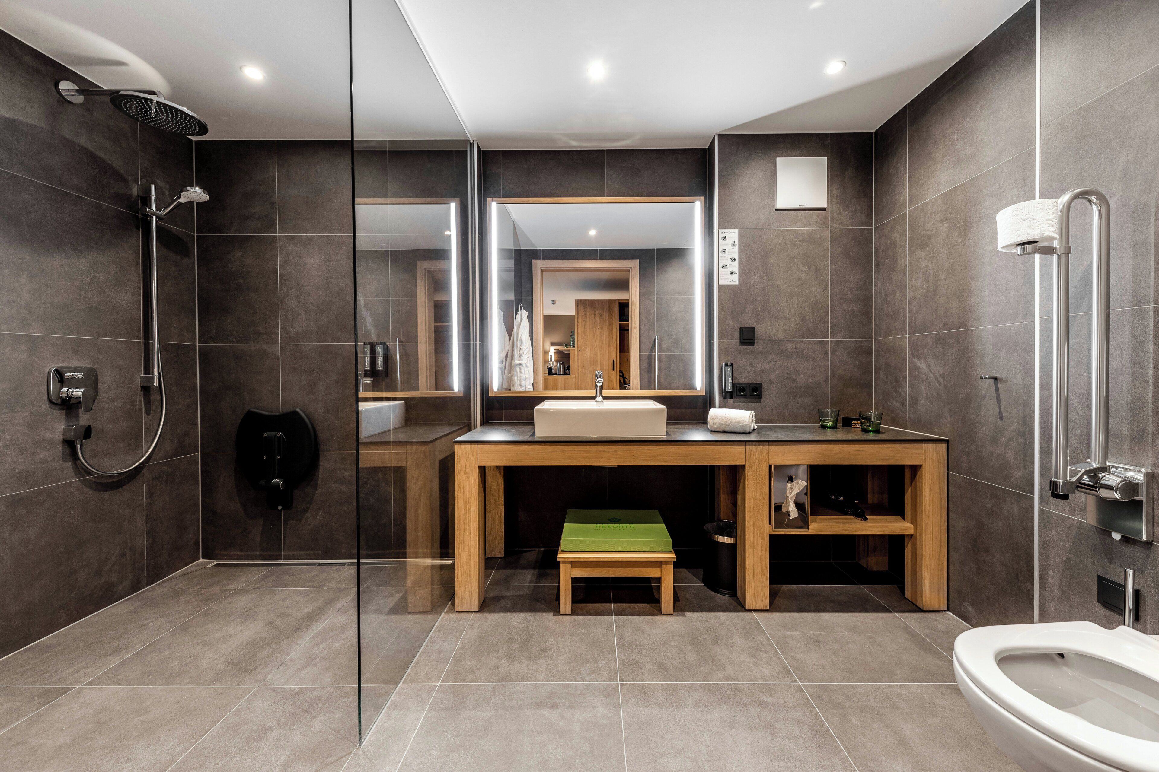Ein modernes Badezimmer mit einer gläsernen Duschkabine, einem hölzernen Waschtisch mit Waschbecken und einer Toilette.