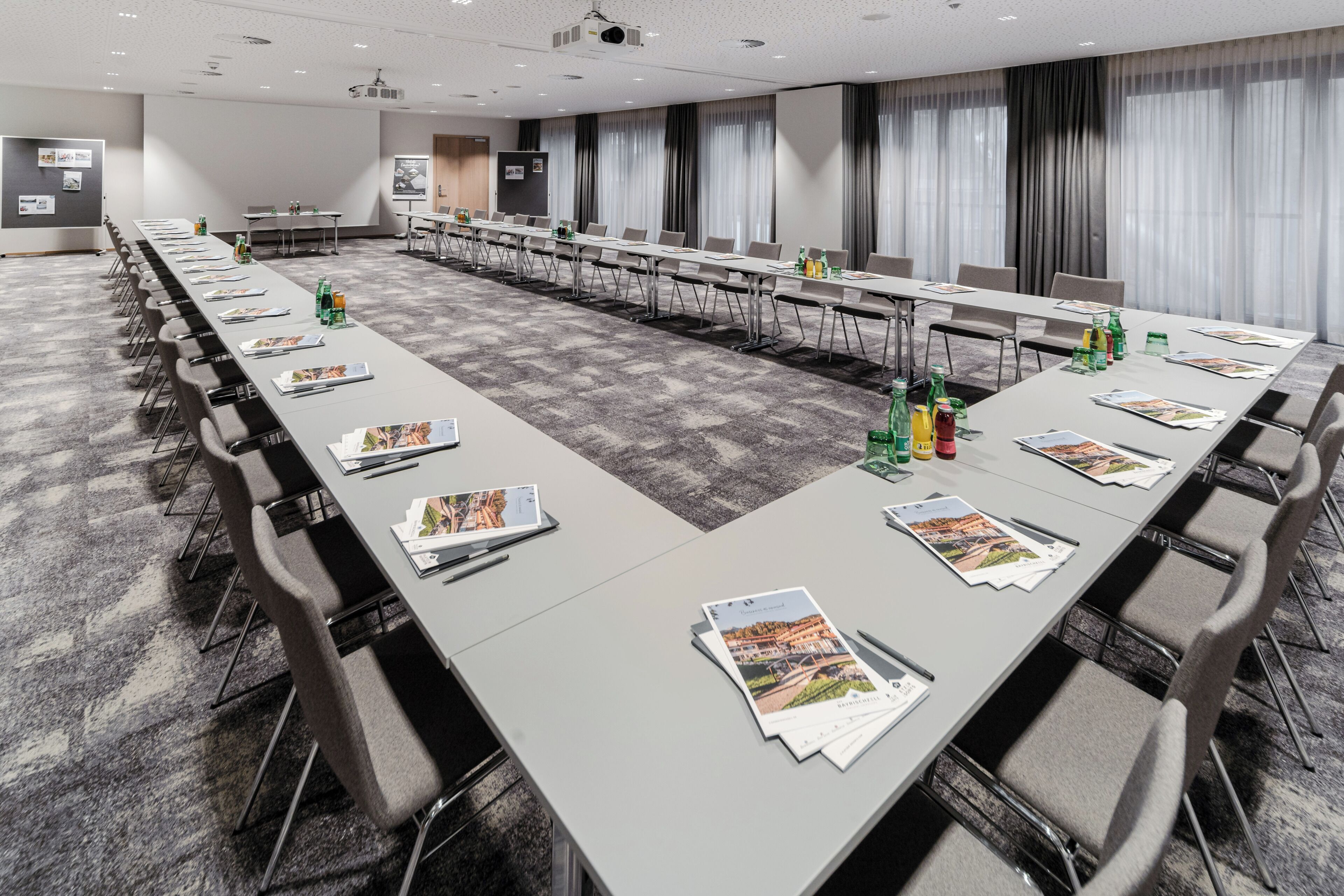 Un salón de conferencias con largas mesas, sillas y folletos informativos.