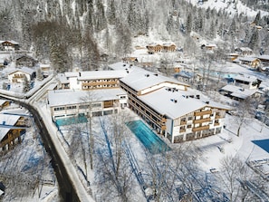A snow-covered resort with multiple buildings, including a large hotel with a swimming pool.