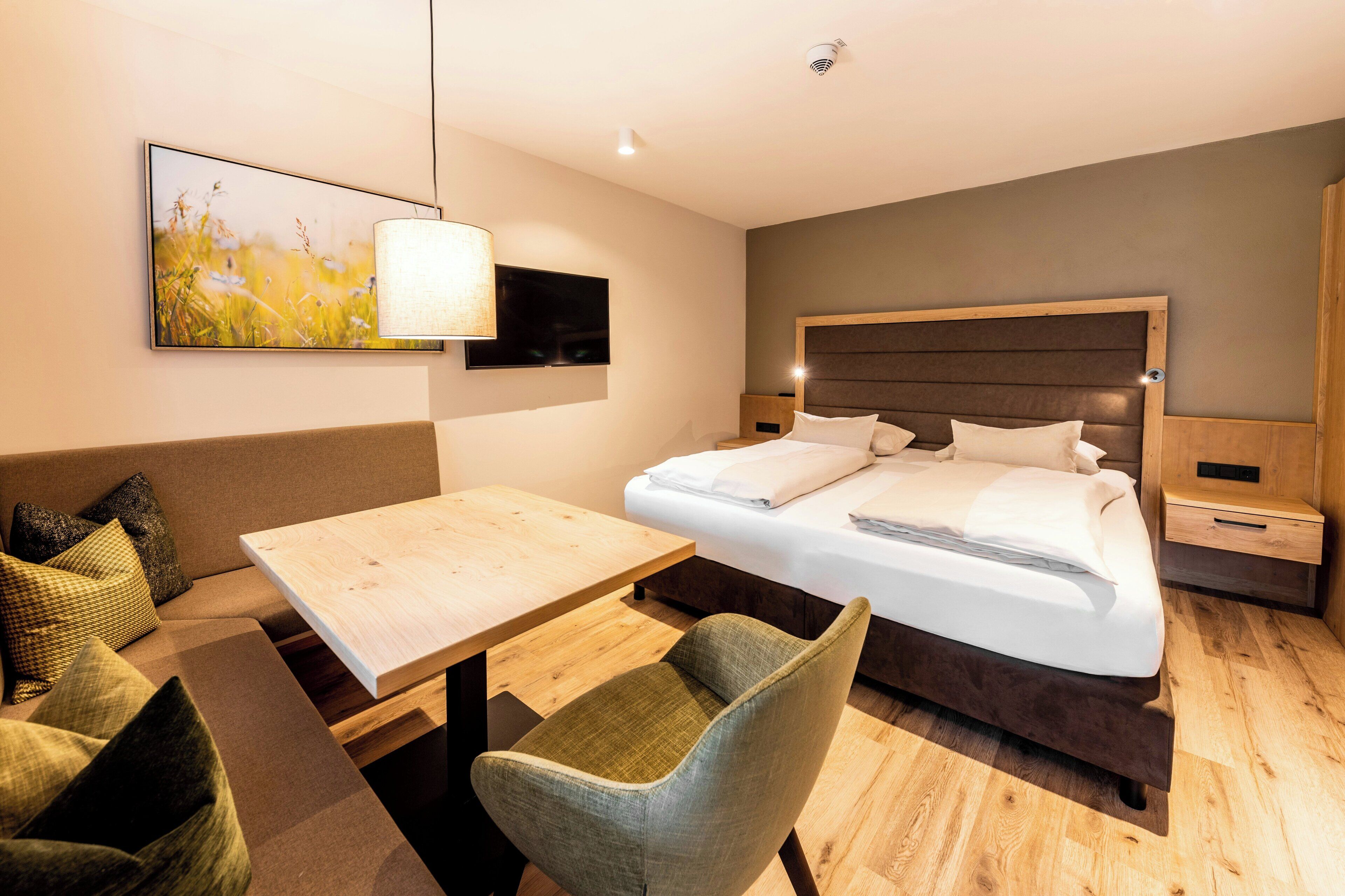 Habitación de hotel moderna con cama, escritorio, silla, televisor y un cuadro en la pared.