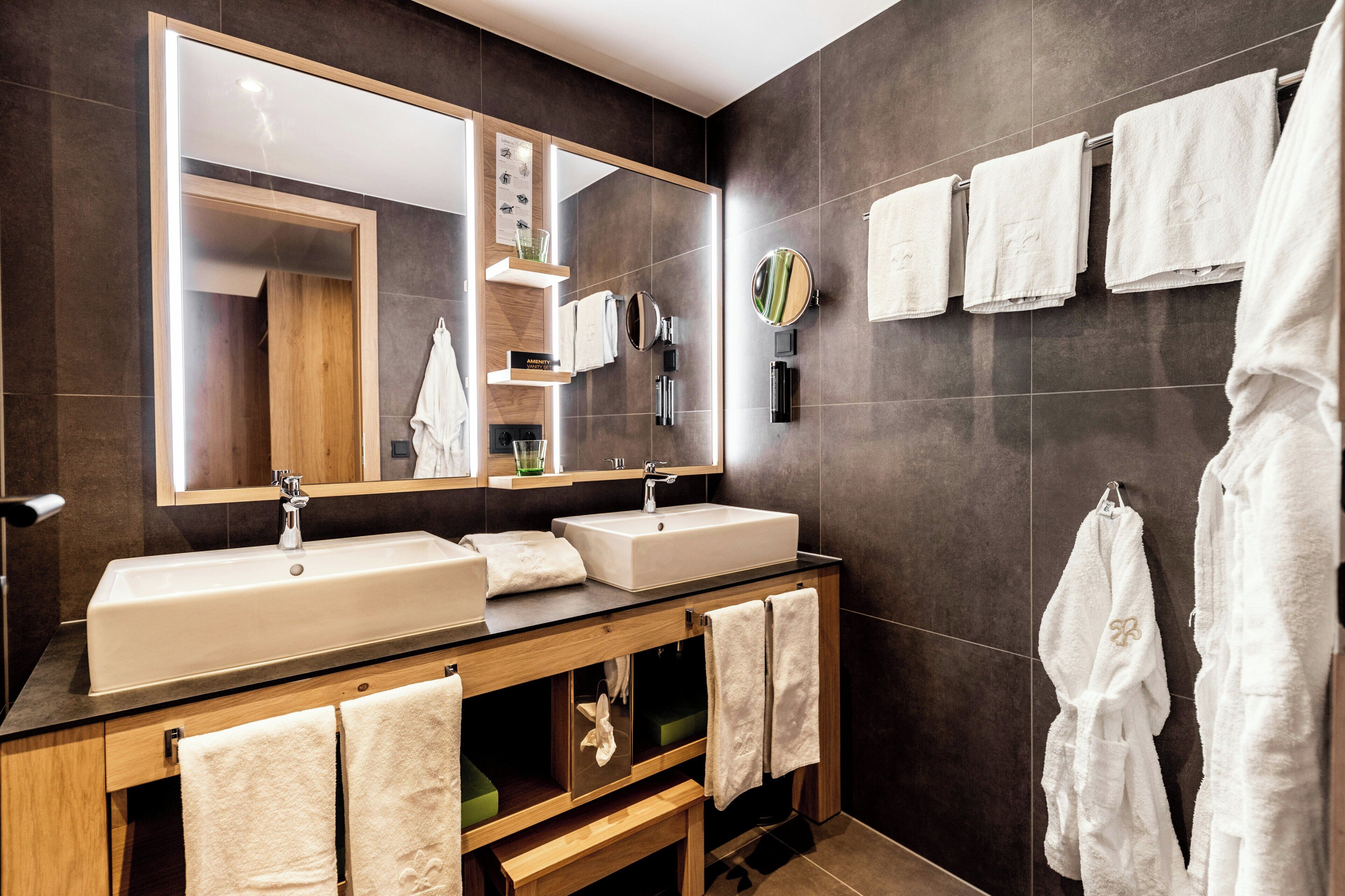 A modern bathroom with two sinks, a large mirror, and multiple towels.
