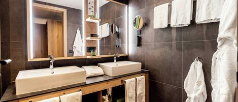 A modern bathroom with two sinks, a large mirror, and multiple towels.