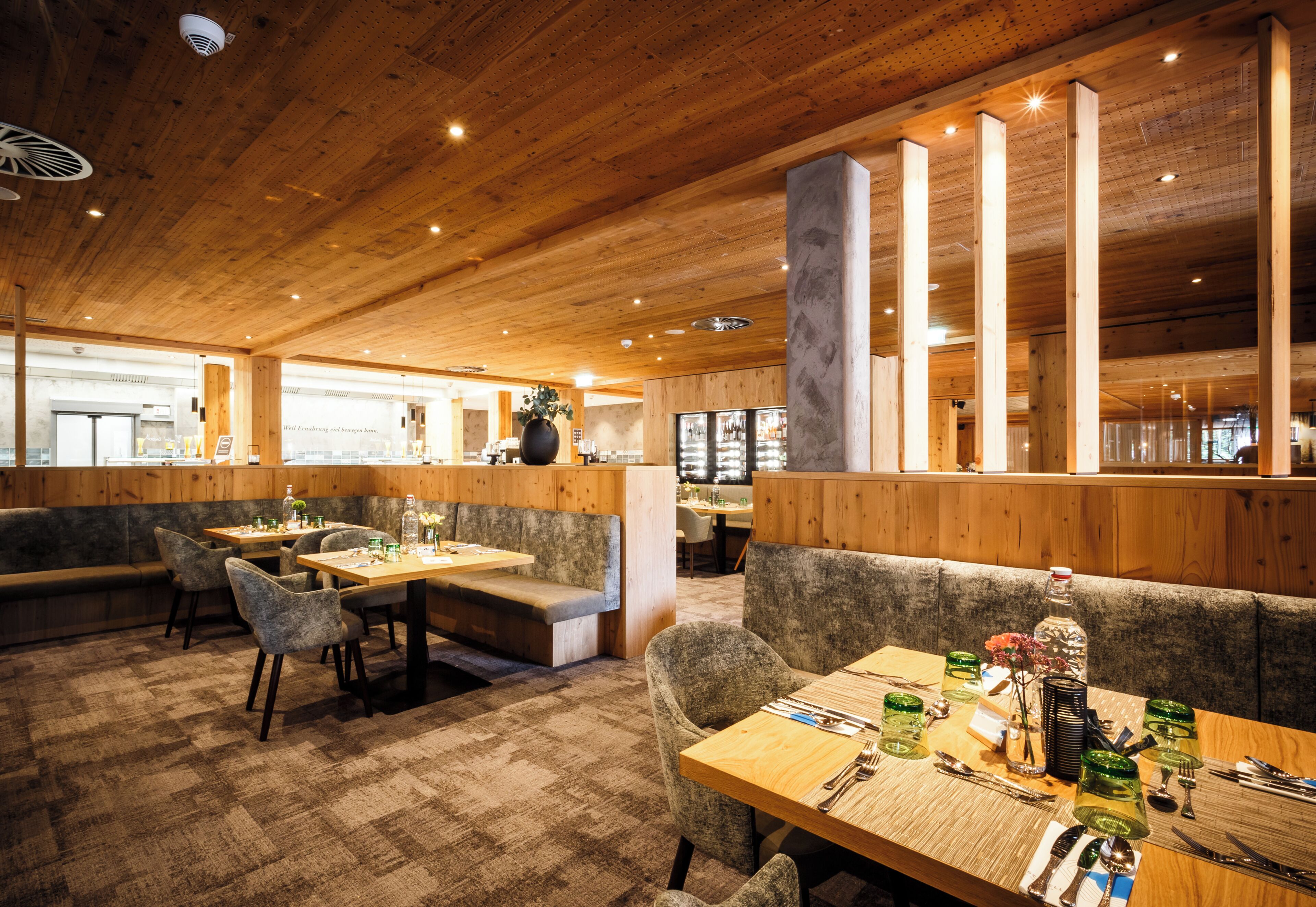 A restaurant interior with wooden beams, cushioned seating, and a bar area.
