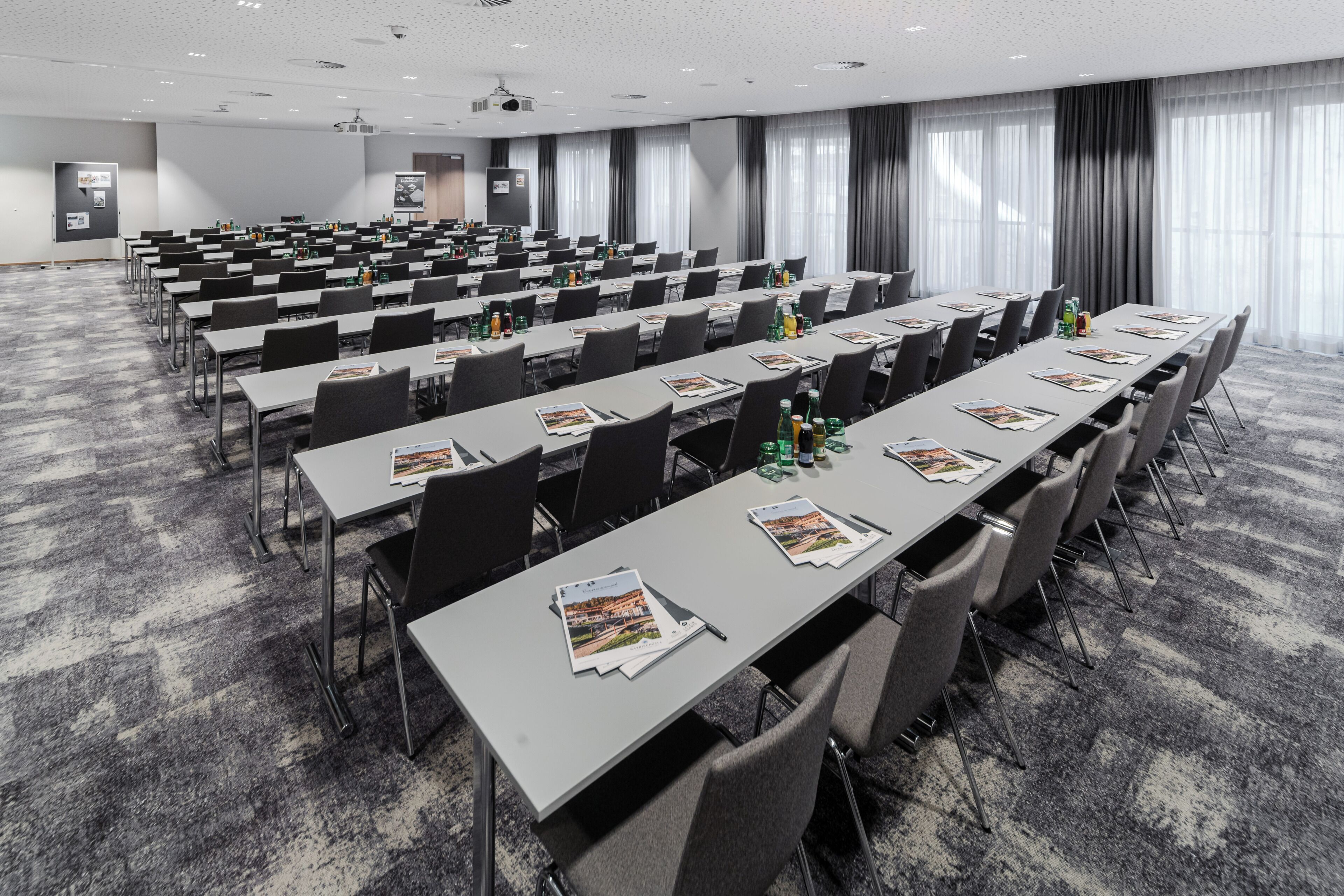 A conference room with rows of tables, chairs, and a projector screen.