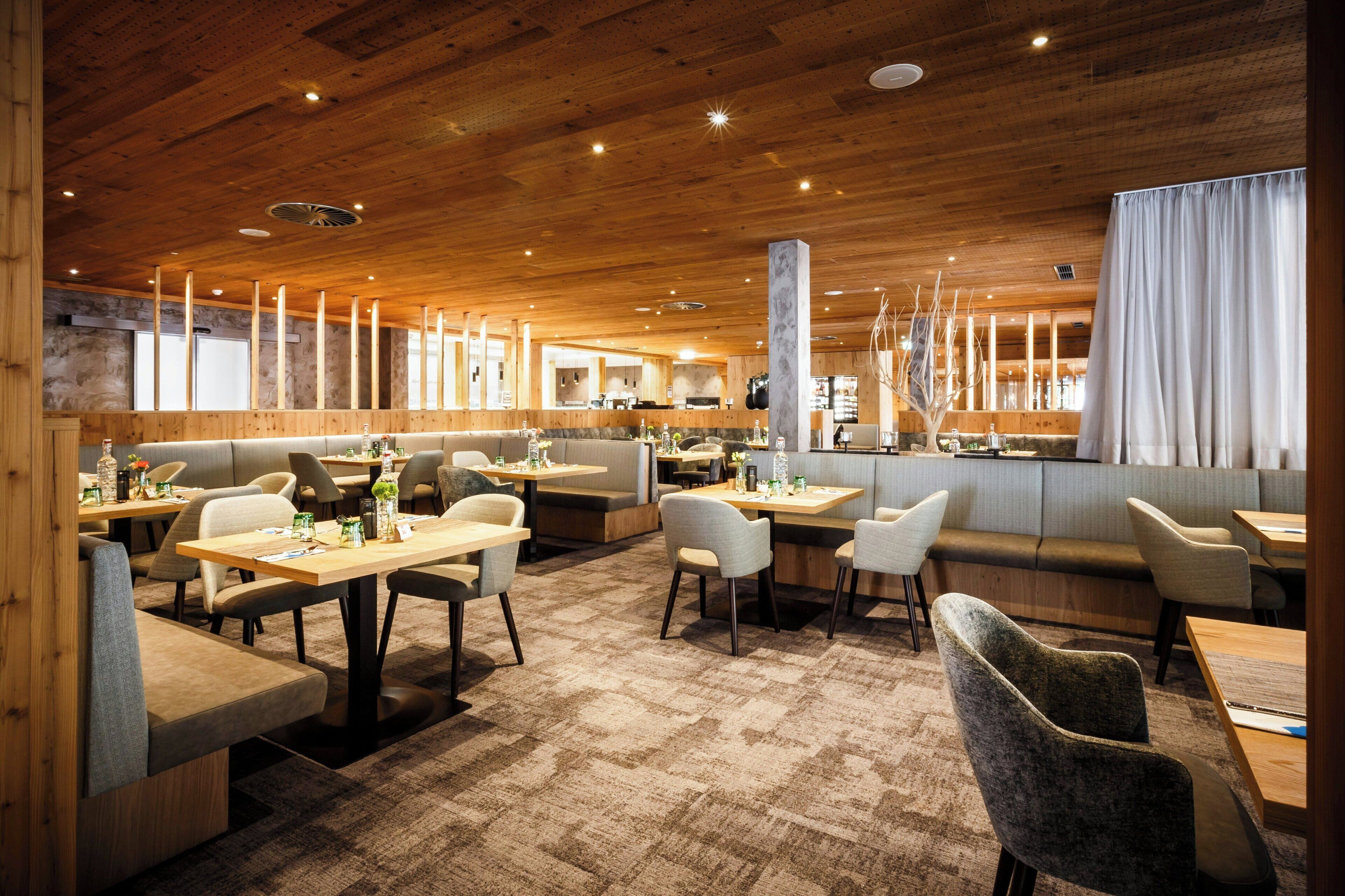 Un restaurante con techo y paredes de madera, mesas, sillas y una zona de bar.