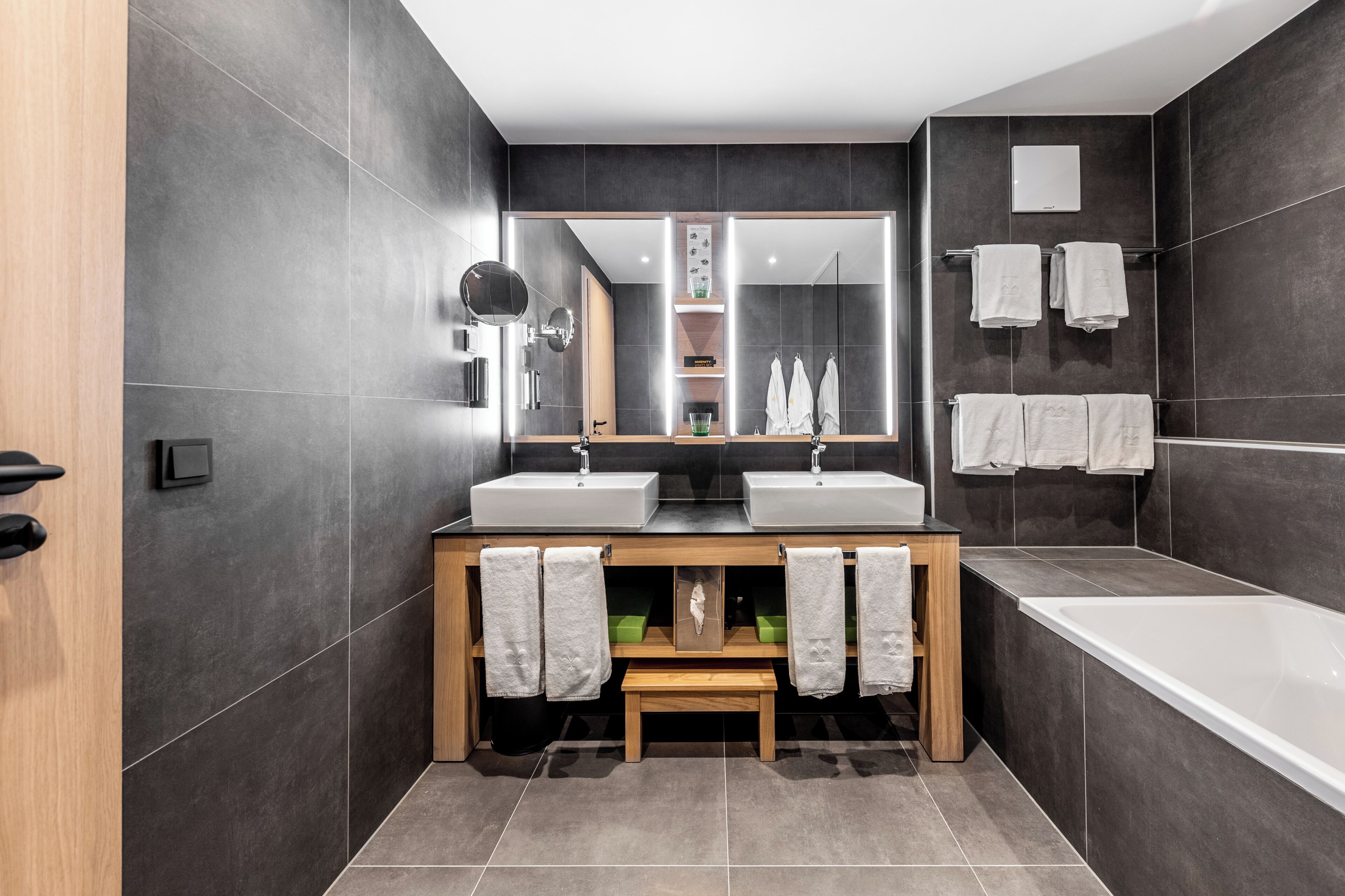 Un baño moderno con dos lavamanos, un espejo grande y una bañera.
