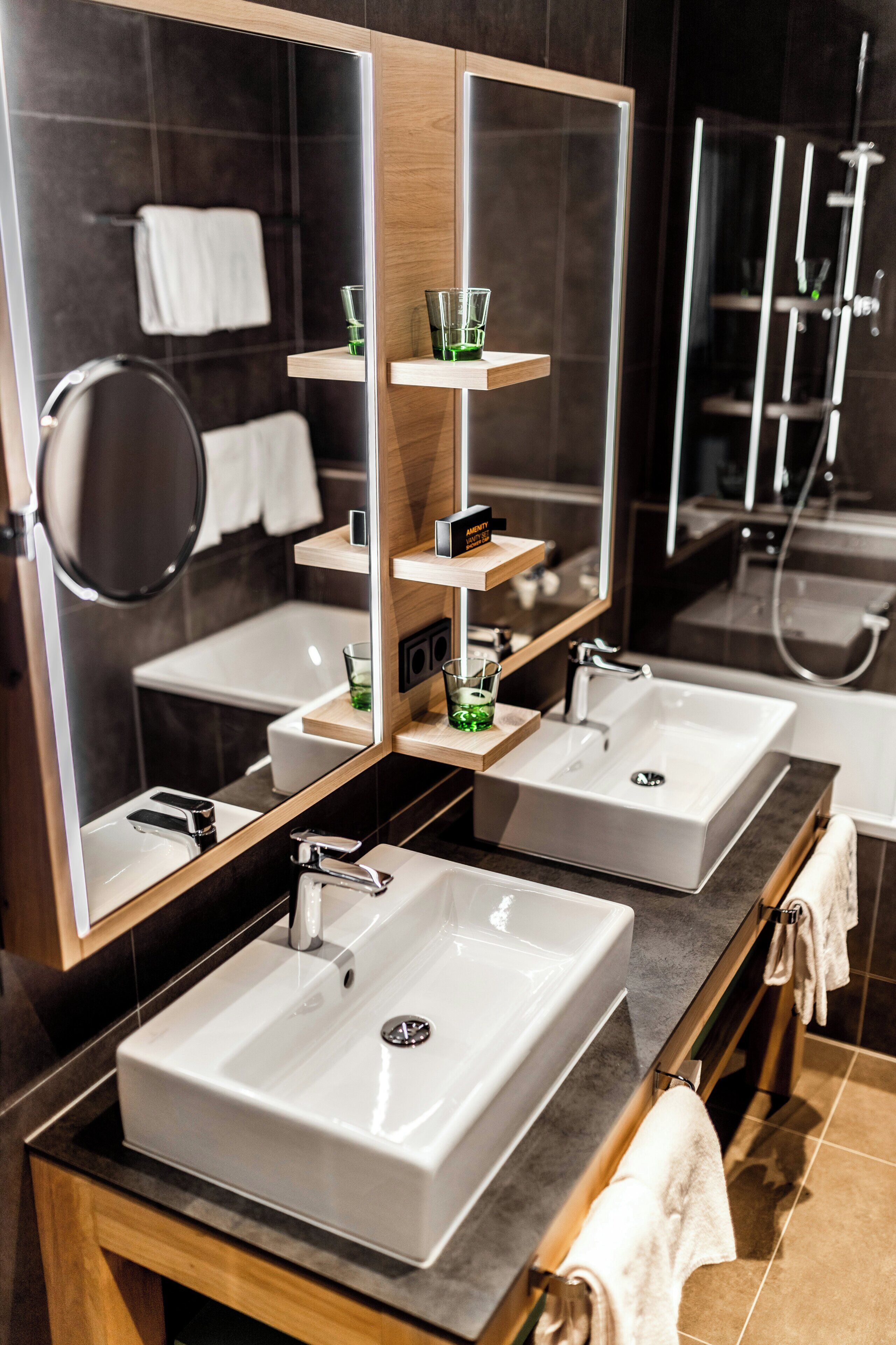 A modern bathroom with two sinks, a mirror, and a shower area.