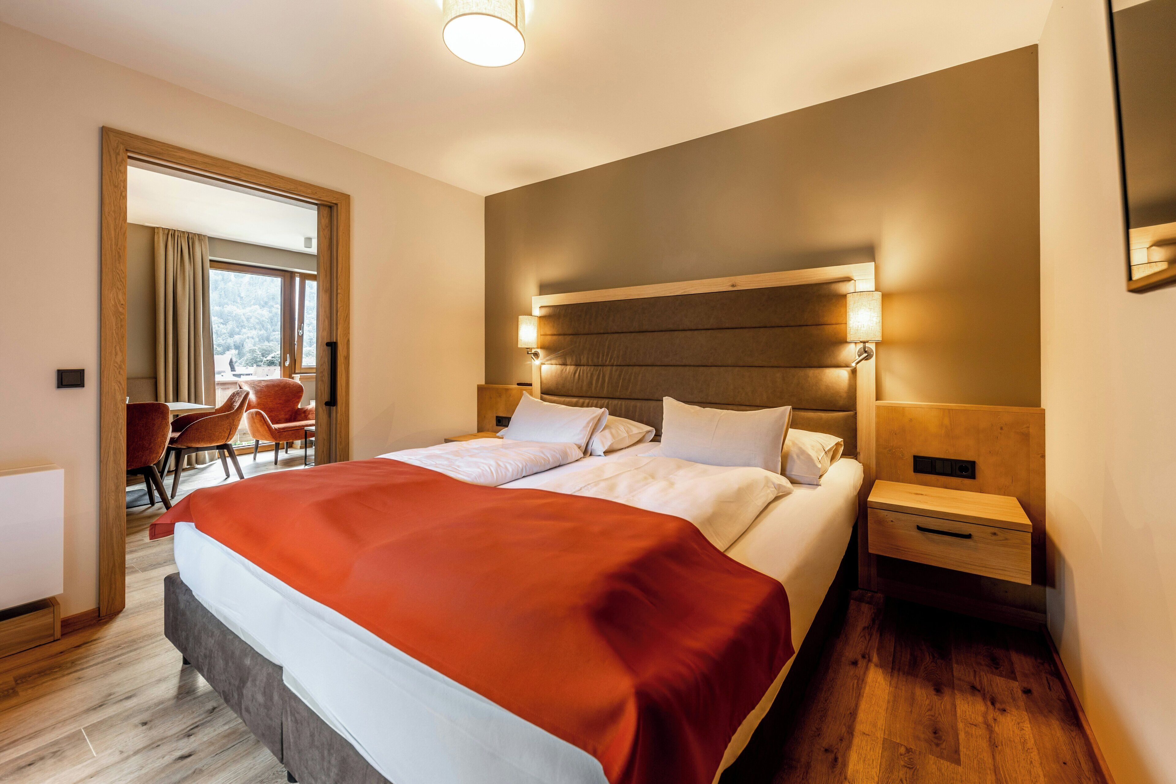 Habitación de hotel con una cama grande, una mesita de noche y vistas al exterior a través de una ventana.