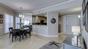A spacious kitchen with a central island, a dining area with a chandelier, and a living area with a lamp. - 6204 Hampton Place - Oceanfront Views, Pool, Spa & So Much More! (Hilton Head Island)