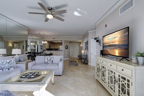 A living room with a ceiling fan, a flat-screen TV, a sofa, a coffee table, and a cabinet. - 6204 Hampton Place - Oceanfront Views, Pool, Spa & So Much More! (Hilton Head Island)