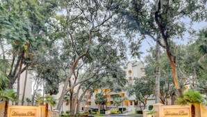 A hotel entrance with a sign reading "Hampton Place," surrounded by trees and a paved walkway. - 6204 Hampton Place - Oceanfront Views, Pool, Spa & So Much More! (Hilton Head Island)