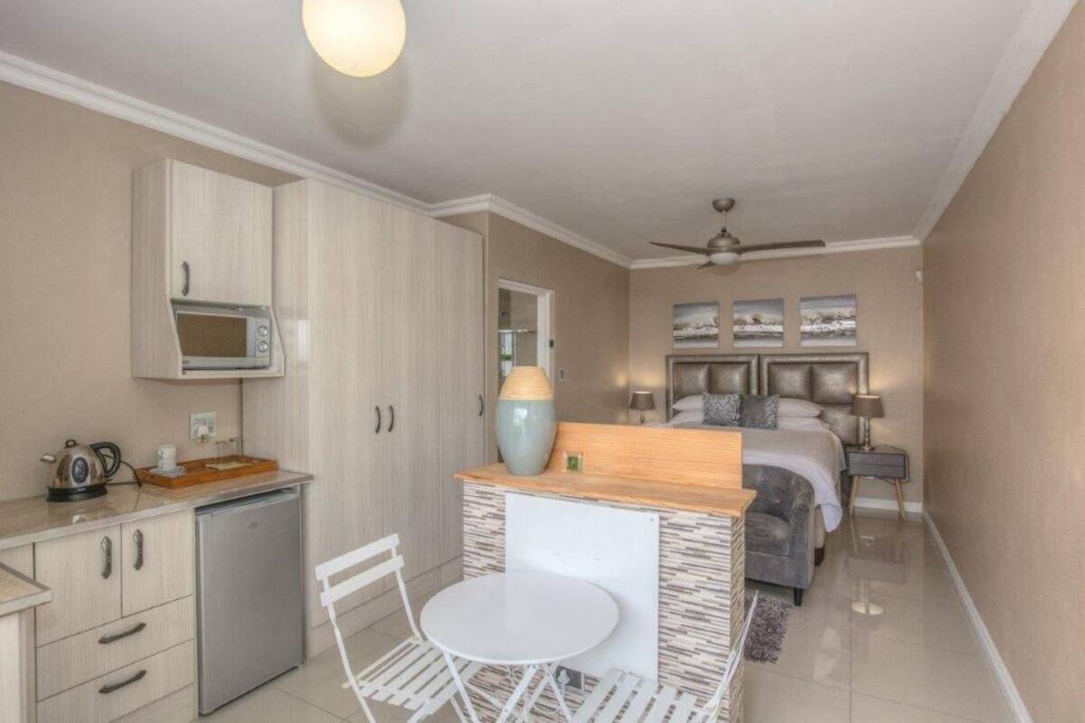 A compact hotel room with a kitchenette, a dining area, and a bed.