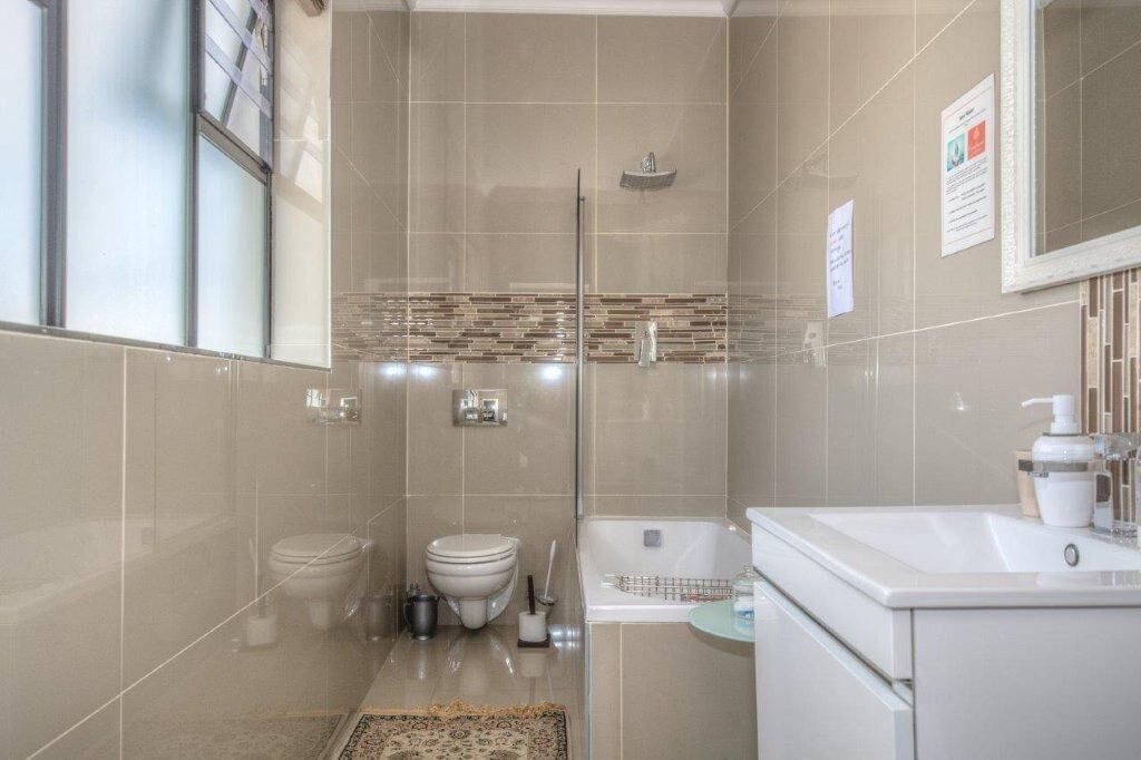 Un baño moderno con cabina de ducha de vidrio, inodoro, bañera y lavamanos.